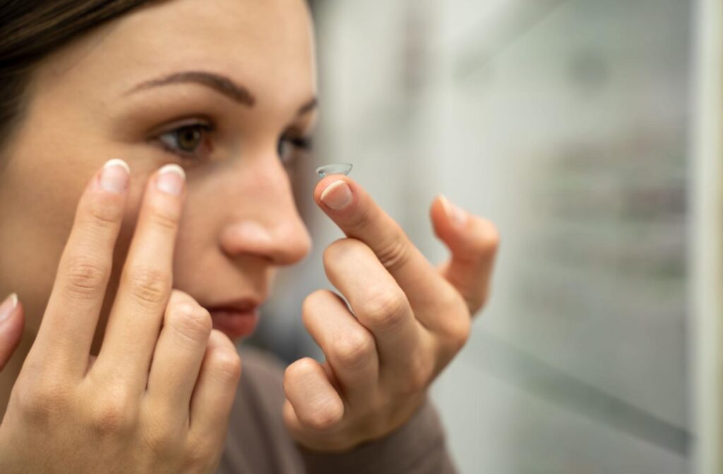 A person holding a contact lens on the tip of their finger about to put it in their eye