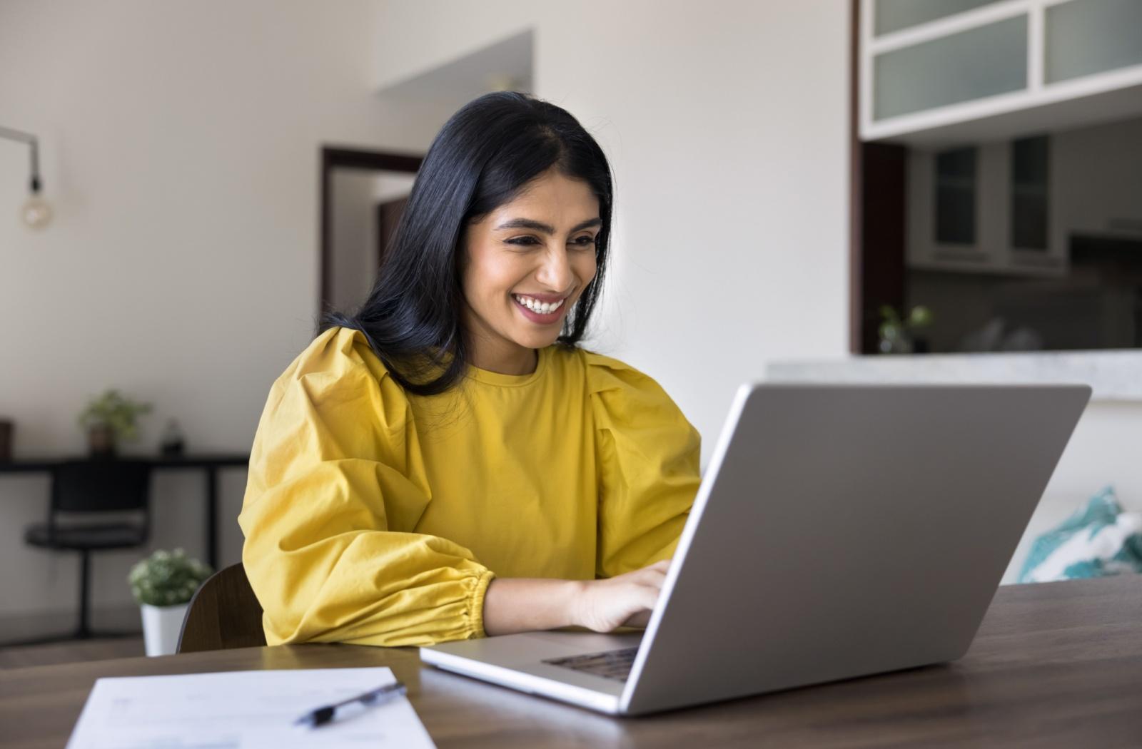 A person smiling while looking at their computer during work
